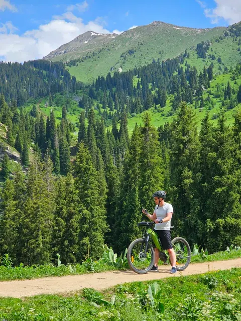 Yakov on an e-bike on a mountain trail among fir trees